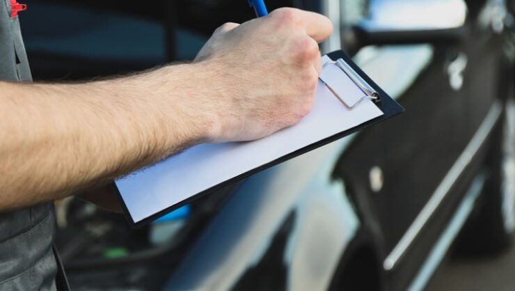 A man writing on a clipboard while holding it in his other hand