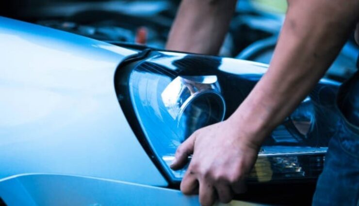 A man repairs the headlight of a car
