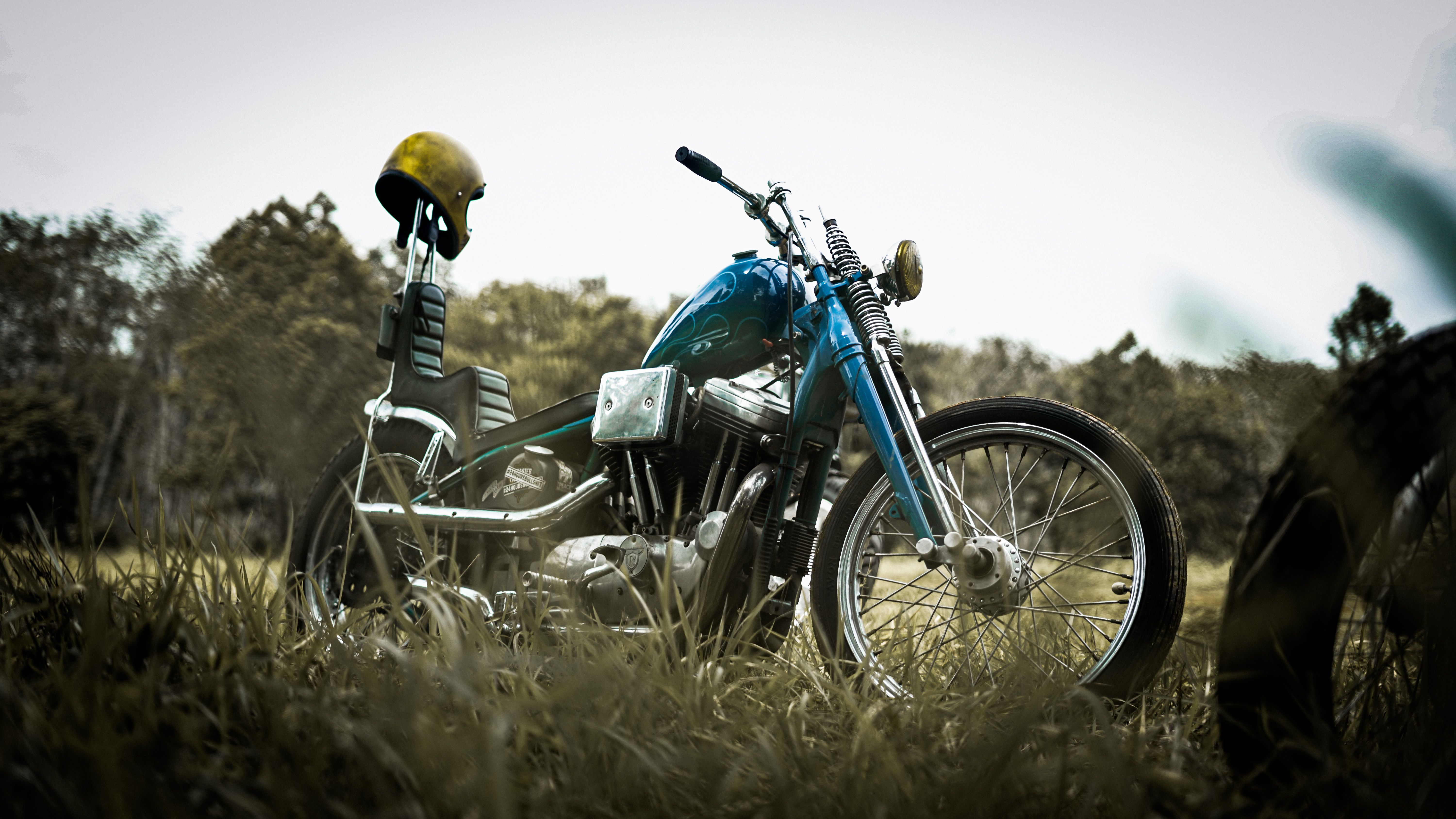 Classic chopper motorcycle with no windshield parked on a grassy field under a cloudy sky