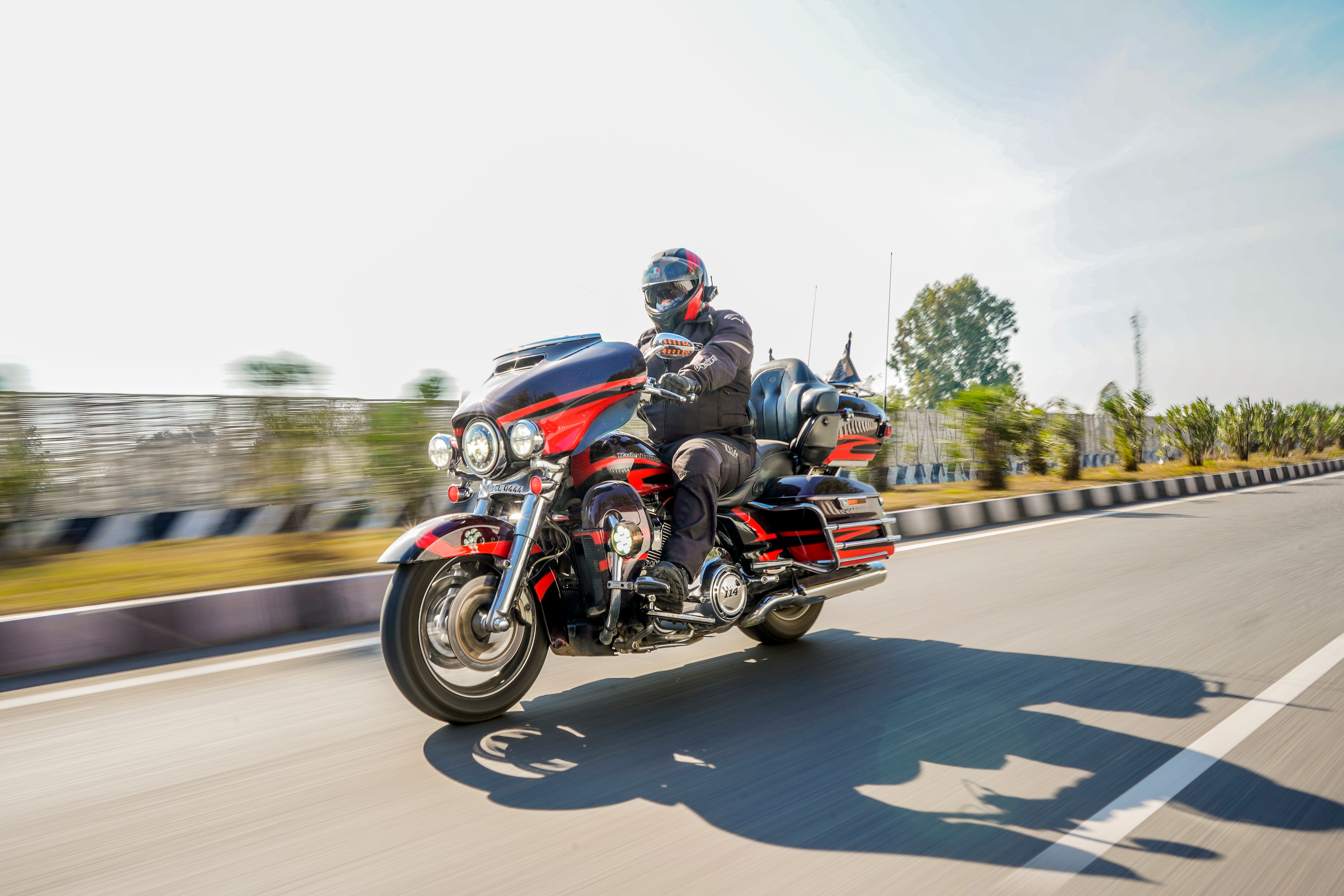 Man riding a Harley-Davidson touring motorcycle on an open highway in daylight