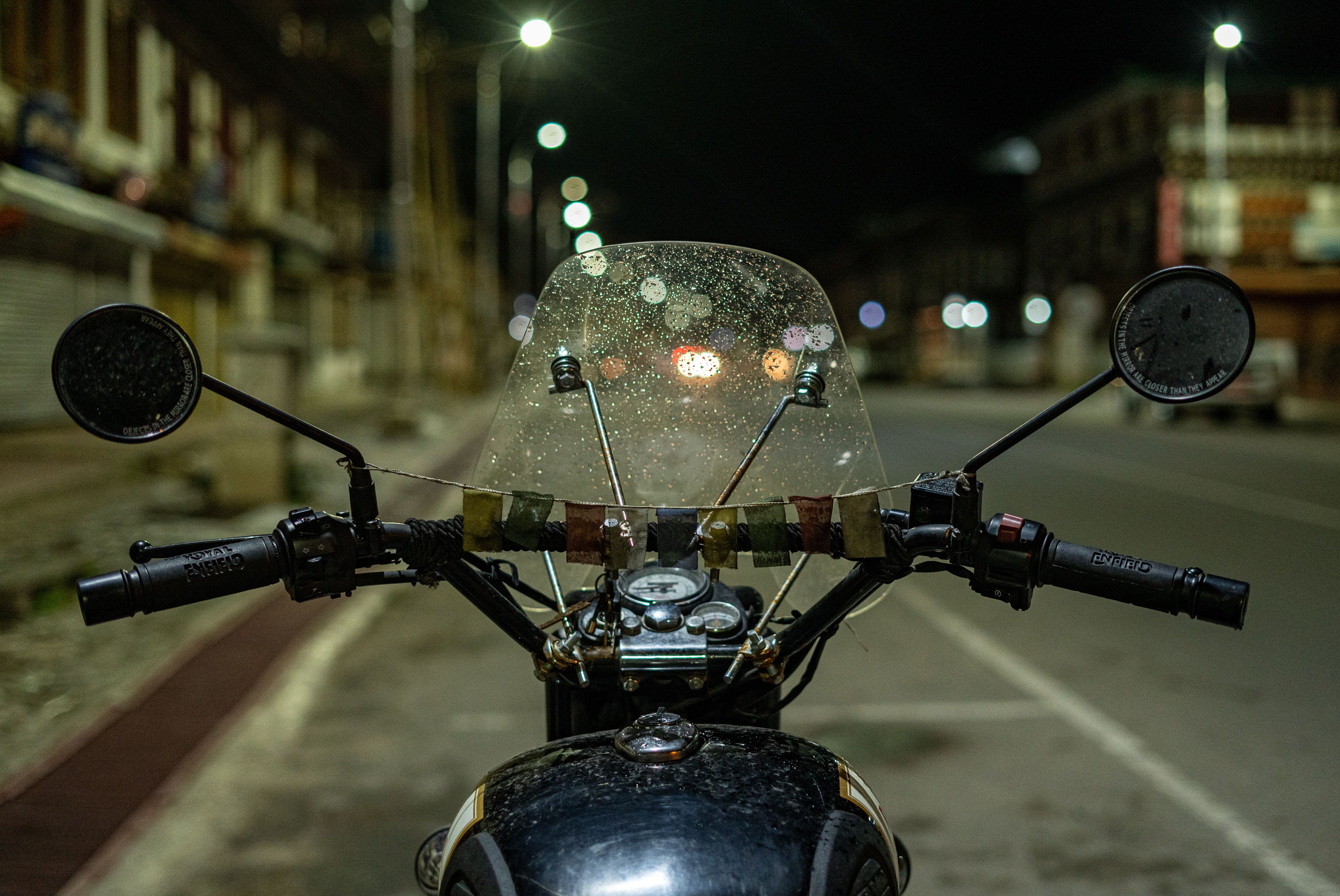 Vintage motorcycle with a rain-speckled windshield parked on an empty city street at night