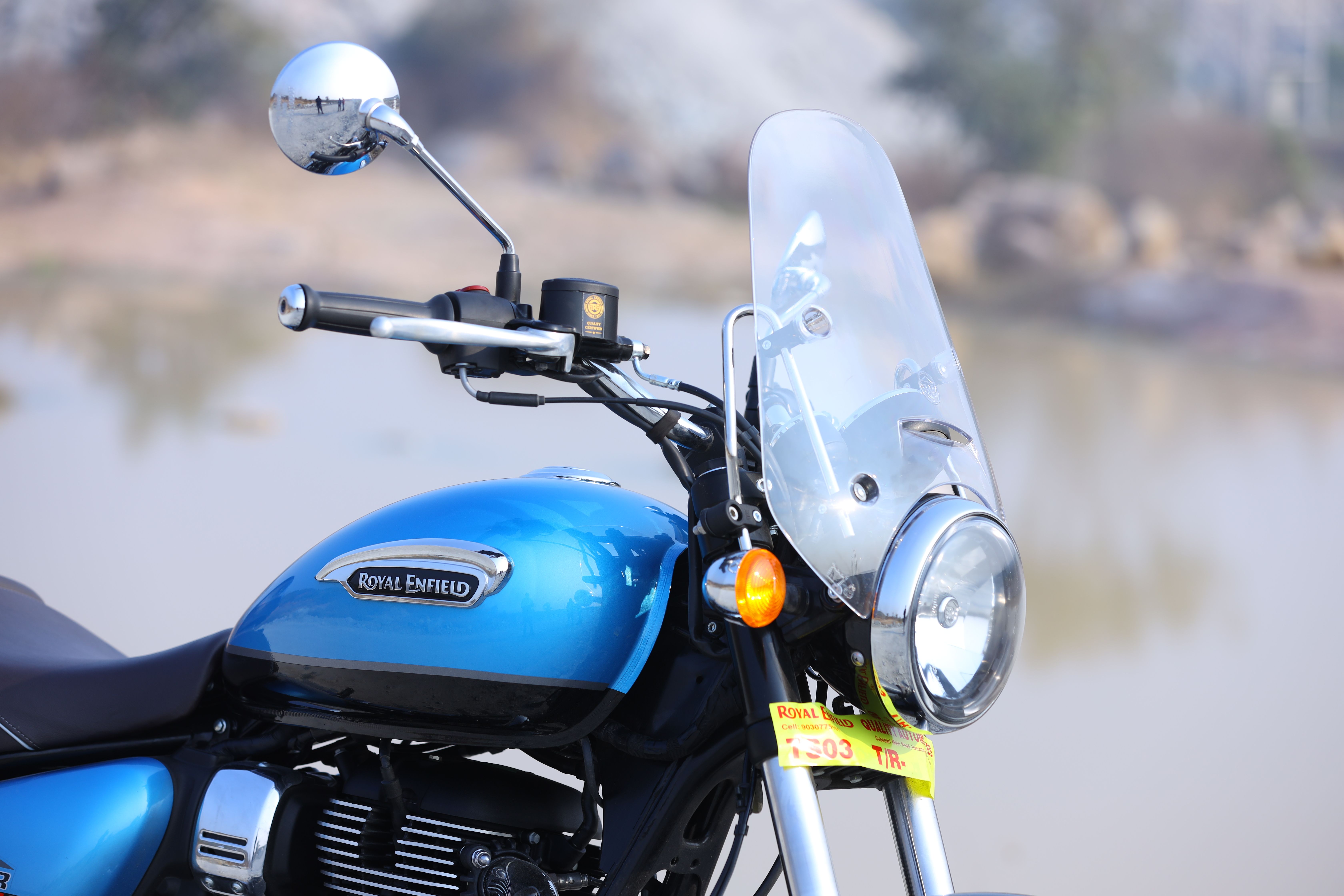 Blue Royal Enfield motorcycle with headlight and tall touring windshield photographed outdoors