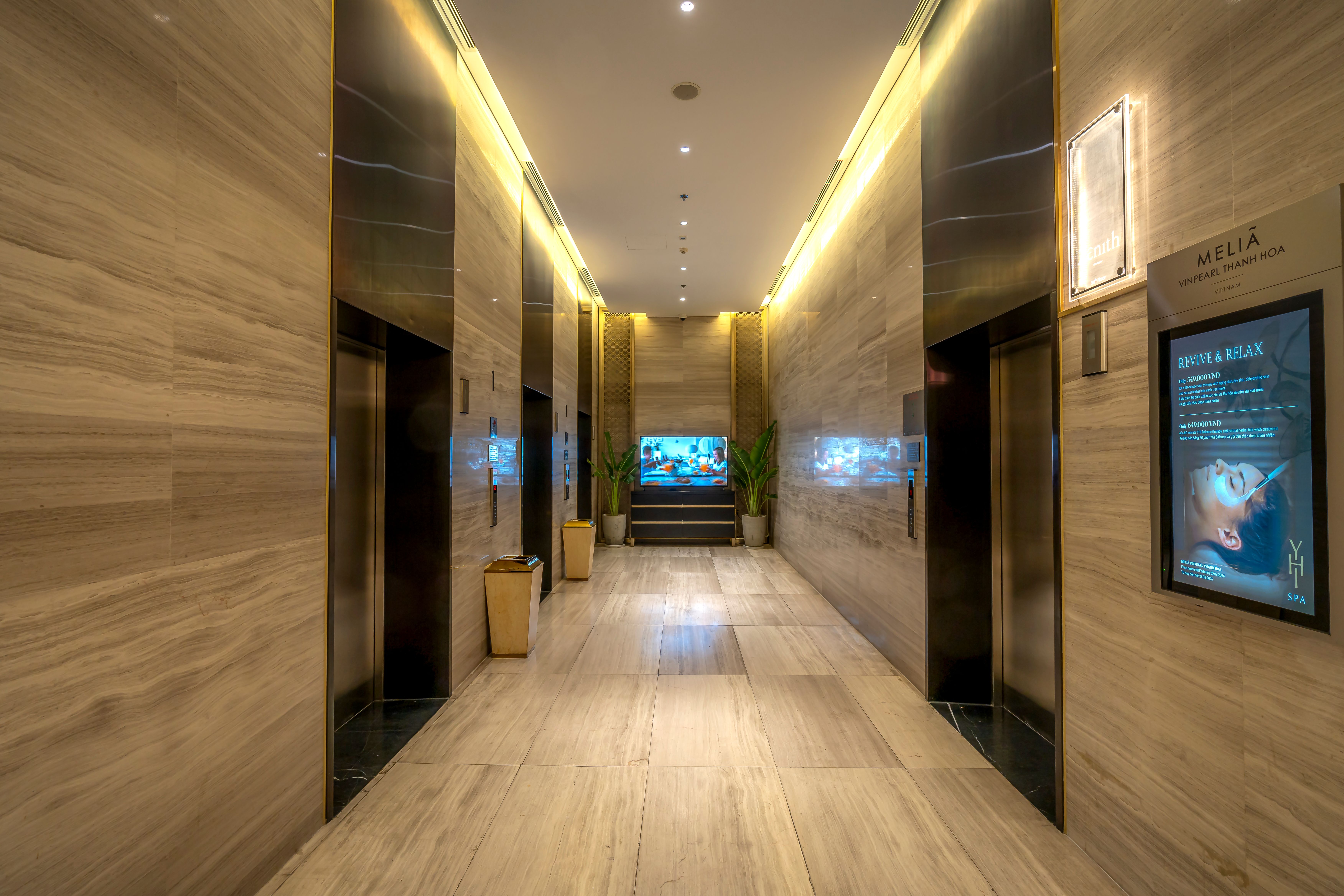 Quiet marble hotel corridor with warm ambient lighting, suggesting privacy and calm in a luxury retreat.