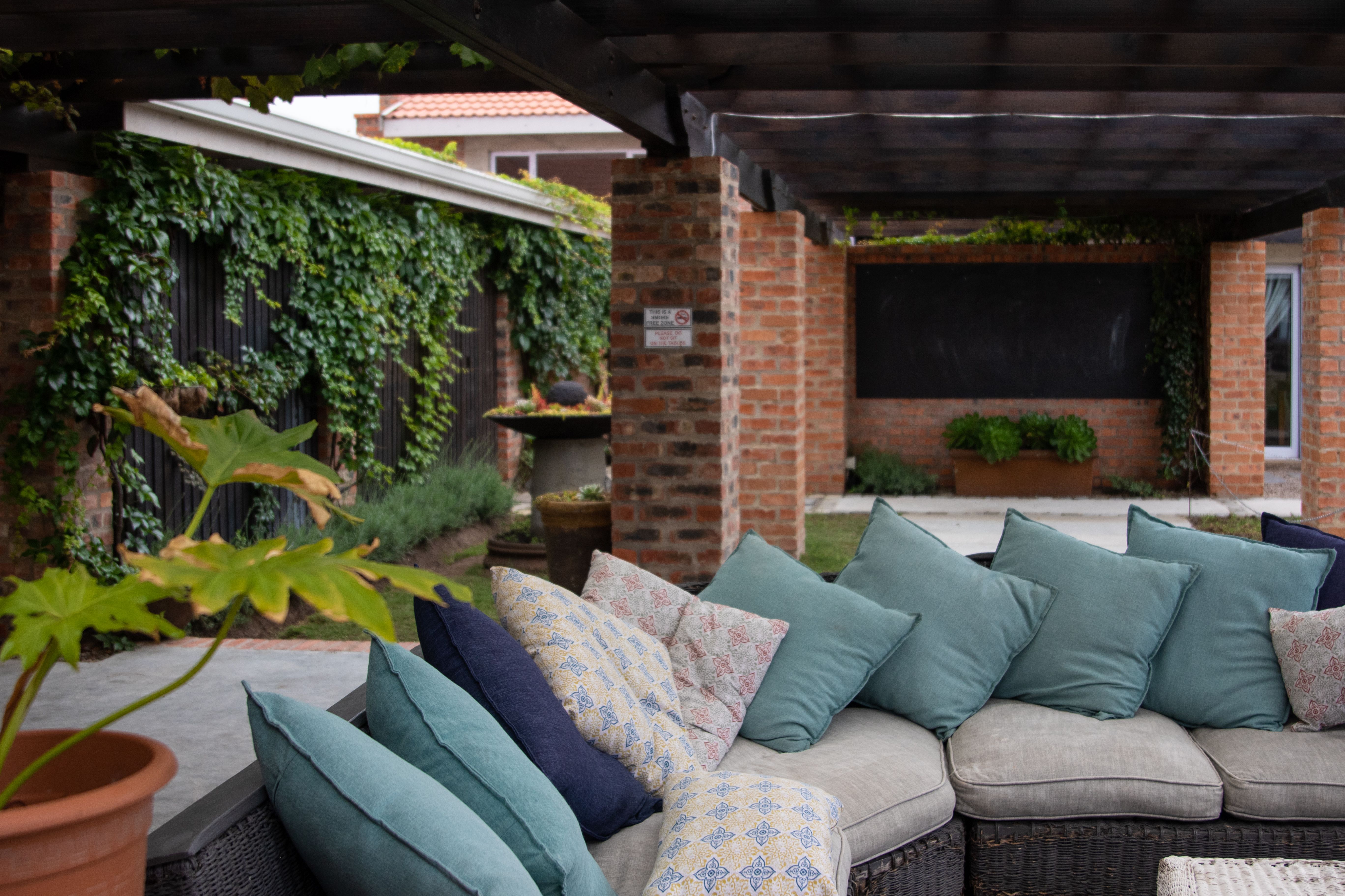 Colorful outdoor cushions and layered greenery bring expressive textile styling to a comfortable patio.