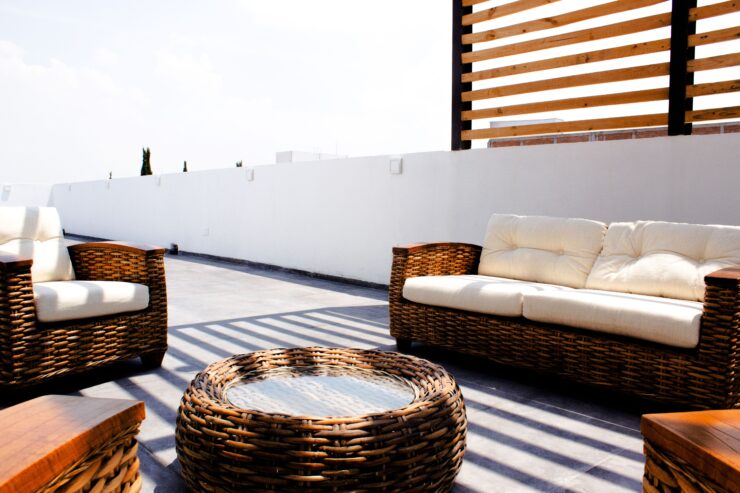 Neutral-toned wicker lounge furniture on a sunny rooftop terrace, blending relaxed fashion-inspired styling with contemporary outdoor design.